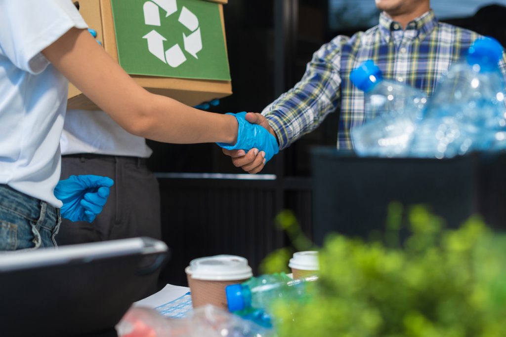 Geschäftsleute, die im Büro an der Trennung von recycelbaren Abfällen in getrennten Behältern arbeiten, nachhaltige Entwicklung und Innovation, Konzept für umweltfreundliches Wirtschaften.