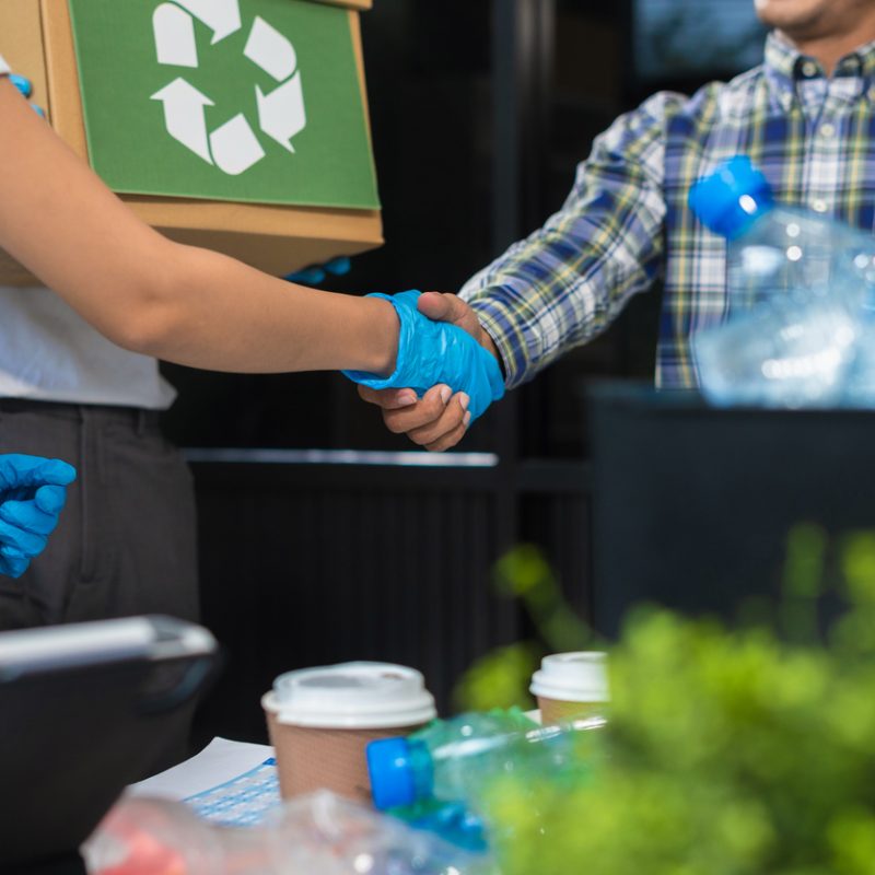 Geschäftsleute, die im Büro an der Trennung von recycelbaren Abfällen in getrennten Behältern arbeiten, nachhaltige Entwicklung und Innovation, Konzept für umweltfreundliches Wirtschaften.