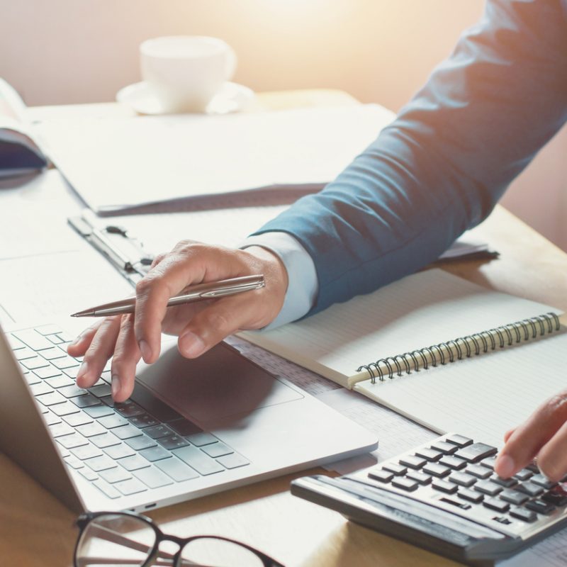 Geschäftsmann bei der Arbeit im Büro mit Taschenrechner und Laptop. Konzept: Finanzen und Buchhaltung
