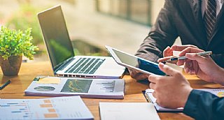 Geschäftsleute bei einer Besprechung mit Laptop, Tablet und Unterlagen