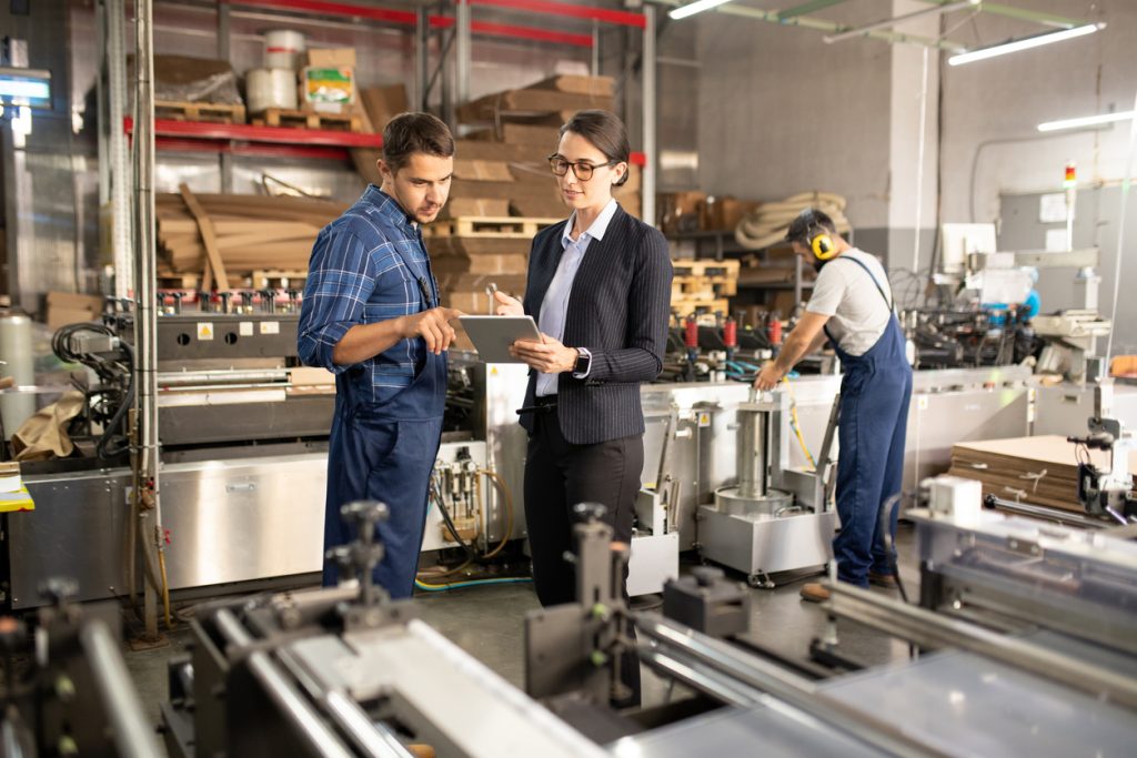 Zwei junge, selbstbewusste Mitarbeiter einer Verarbeitungsfabrik diskutieren über Online-Daten