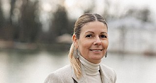 Porträt einer lächelnden Frau vor unscharfem Natur-Hintergrund