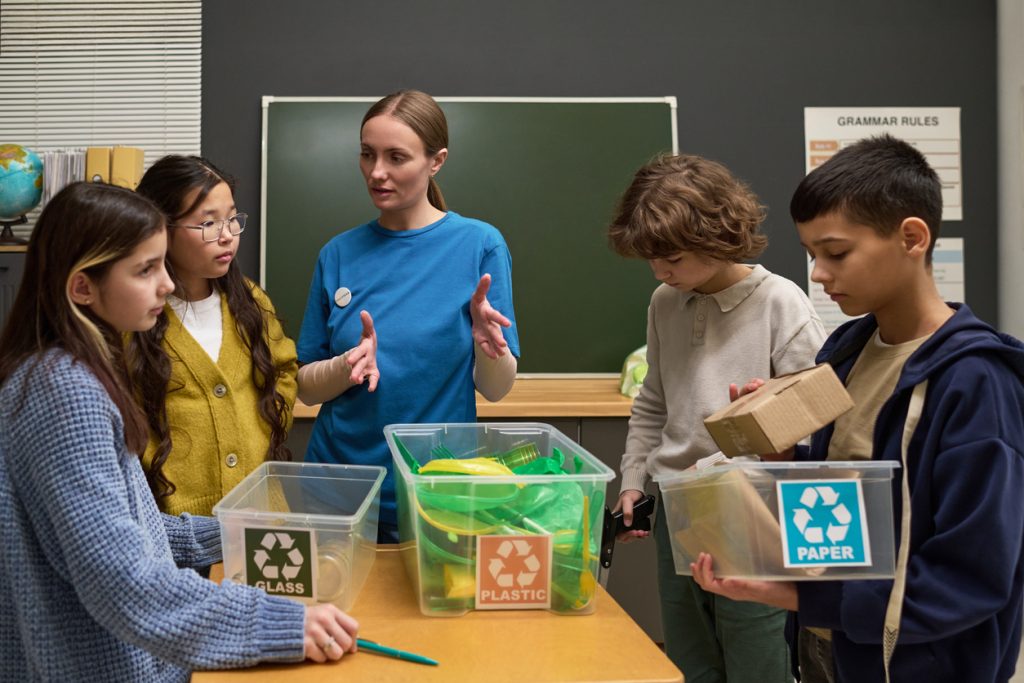 Frau, die Kinder beim Sortieren von Wertstoffen unterrichtet